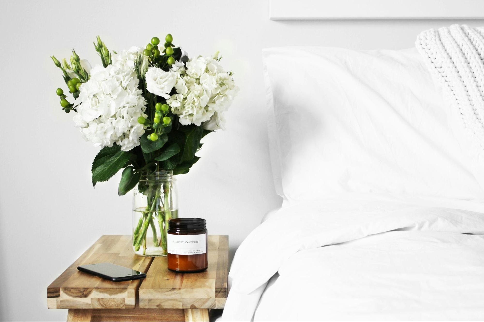  White bed with floral table decor.