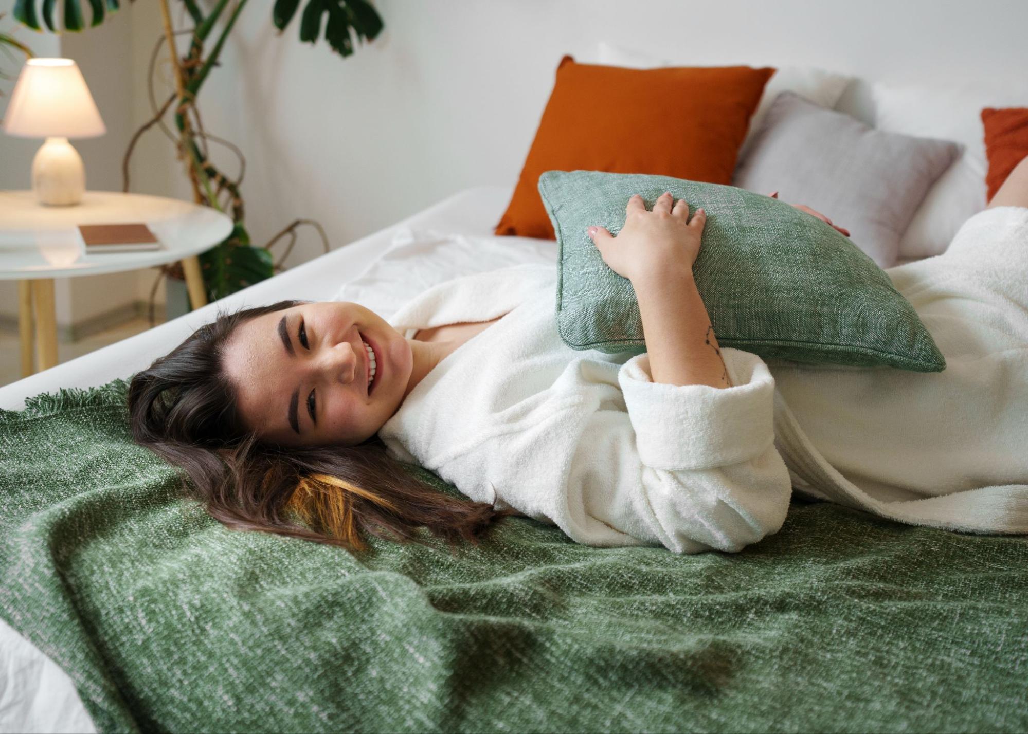 A woman in a bathrobe relaxing on a bed